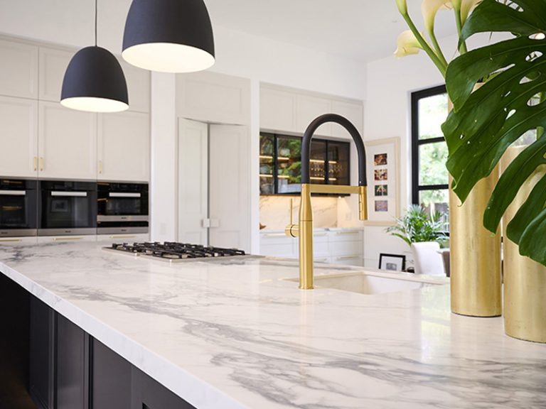 Custom kitchen stone counter top by Trend Stone. Sleek gold and black taps and gold vases